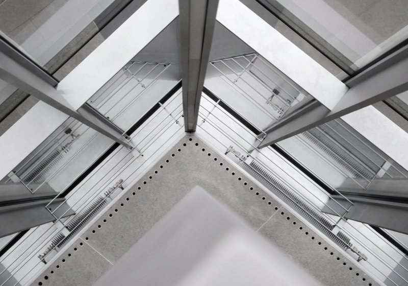 Fragment of office building interior featuring corner of structural glazing. Hi-tech architecture made of steel / aluminum and glass. Material background on the subject of construction industry.