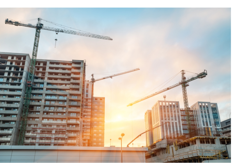 Construction of modern altitudinal buildings of concrete and glass early in the morning during sunrise